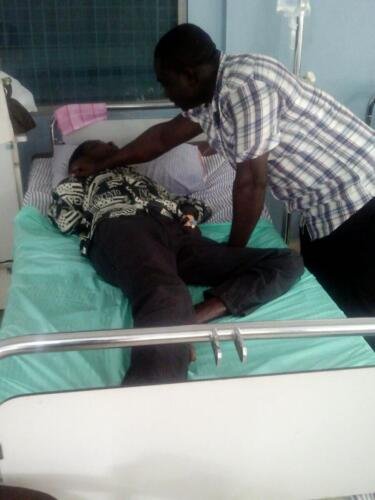 Student Samuel praying for the sick at the hospital